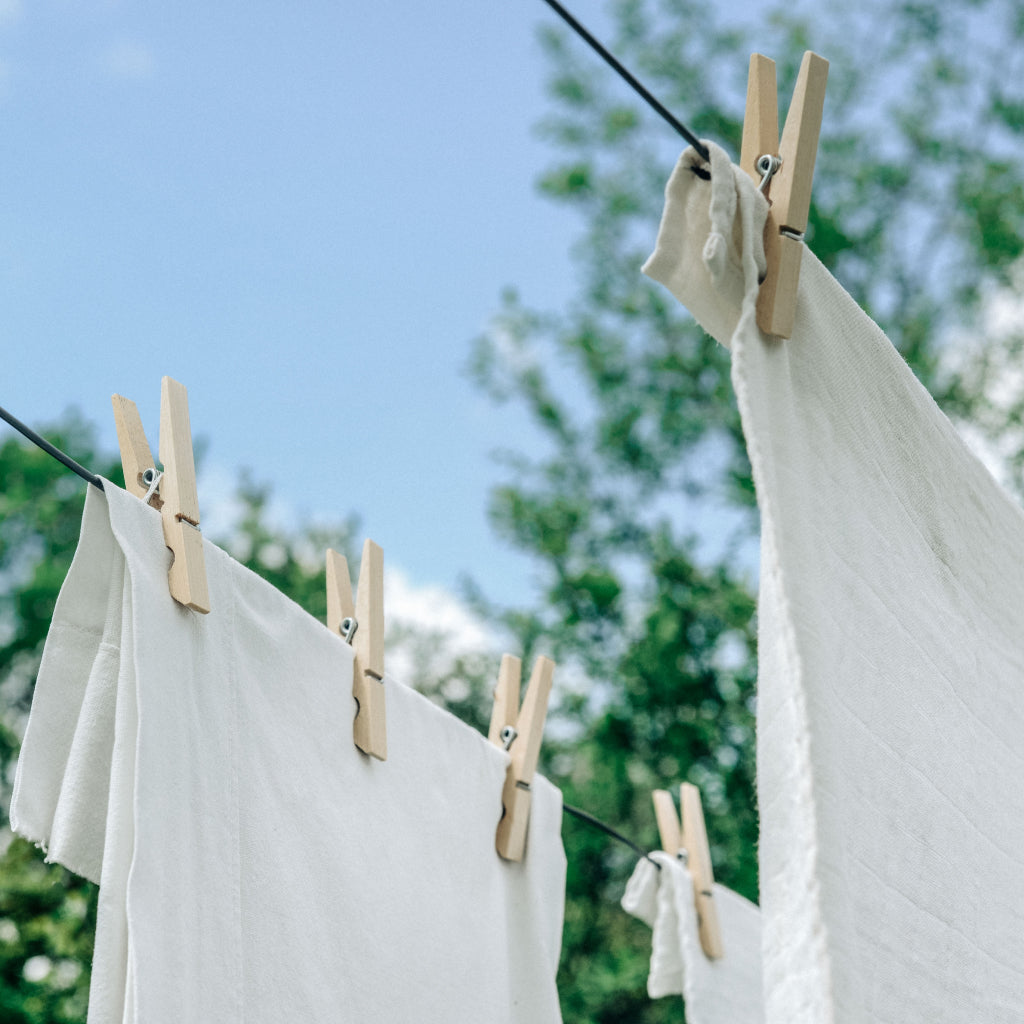 Mosquito repellent tshirts hanging on clothesline with wooden pegs. These shirts last 70+ washes and are still effective at preventing mosquito bites after normal washing.